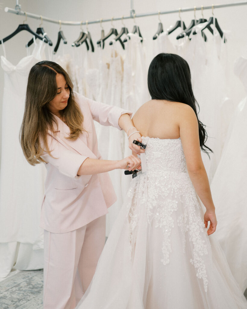 Bridal stylist adjusting wedding dress during fitting at Candè Bridal Boutique Kelowna BC